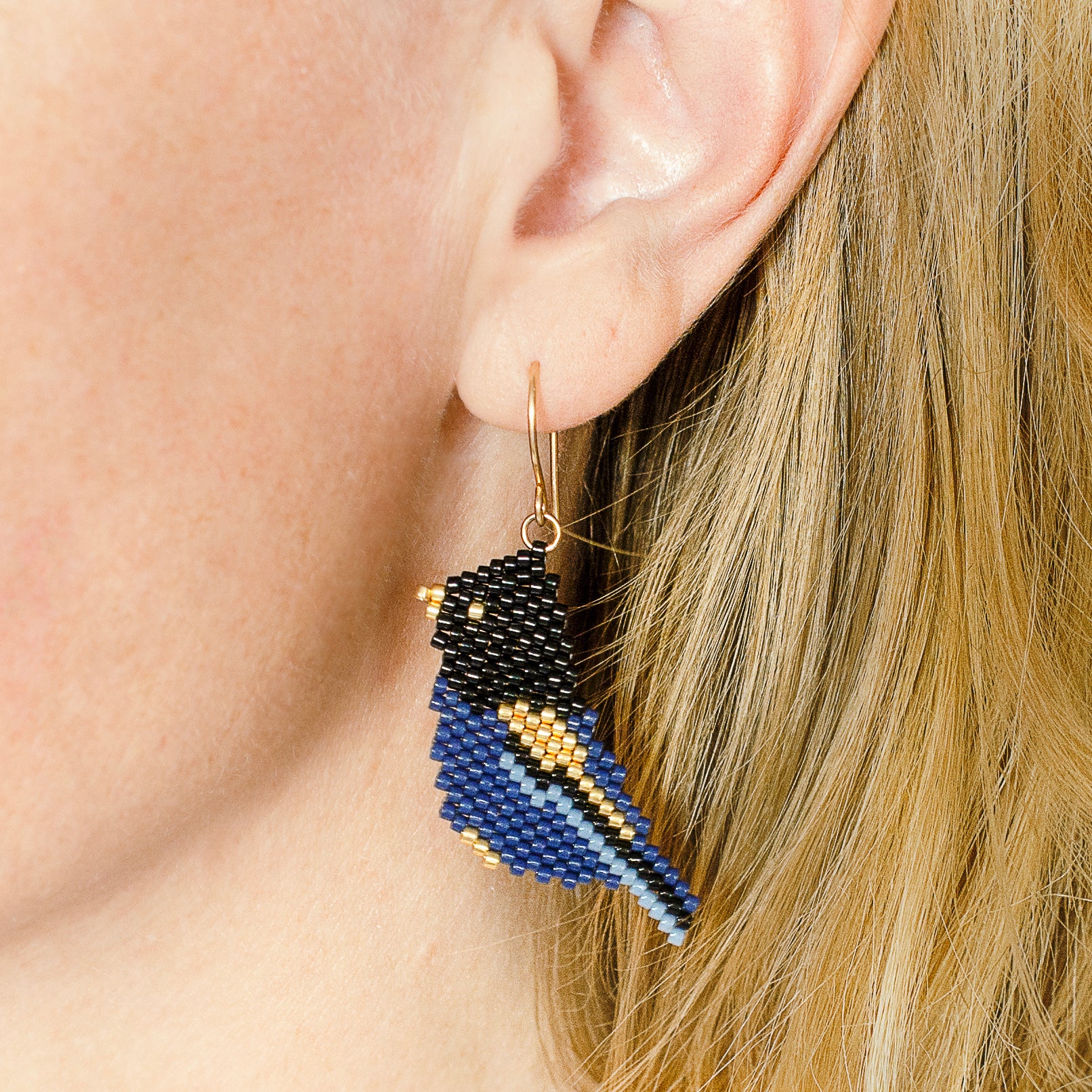 Model wearing the Cobalt Crested Steller's Jay beaded drop earrings to show how they hang
